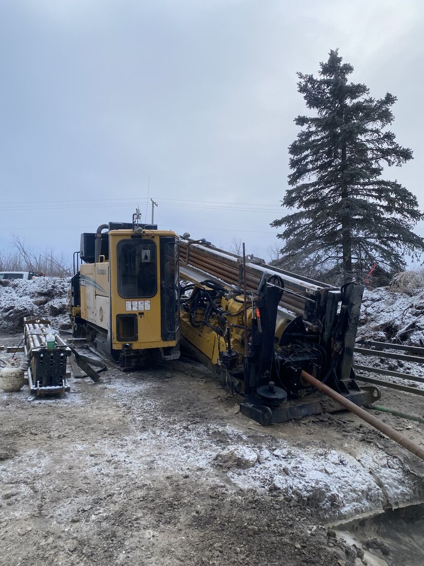 Horizontal directional drill rig on frozen, snow-crusted ground on an overcast winter morning