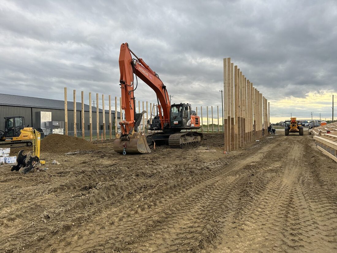 Hitachi excavator digging beside a compact excavator during post-frame building construction