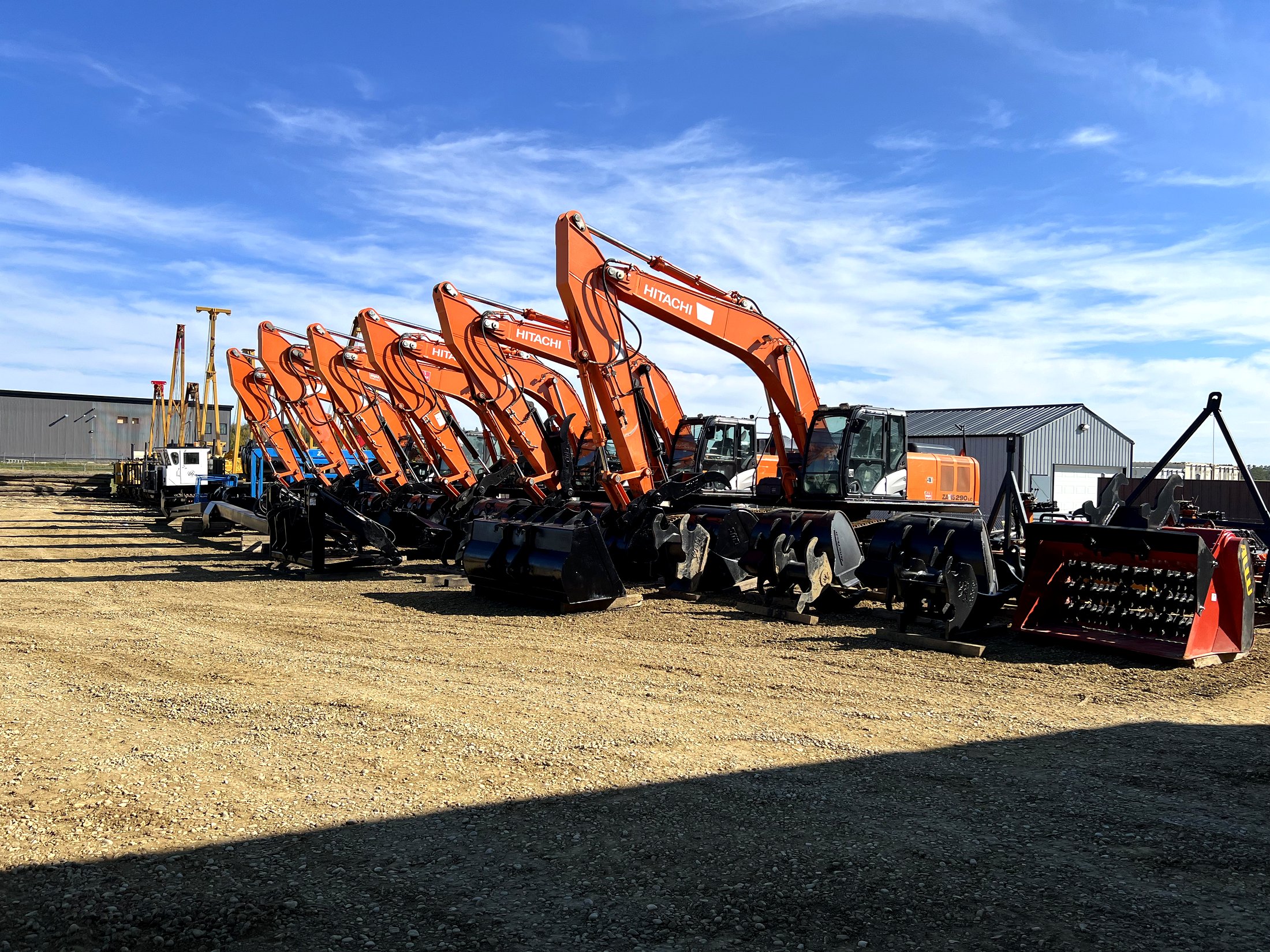 Hitachi ZAXIS 290LC excavator at the head of a row of Hitachi excavators staged with attachments in the equipment yard