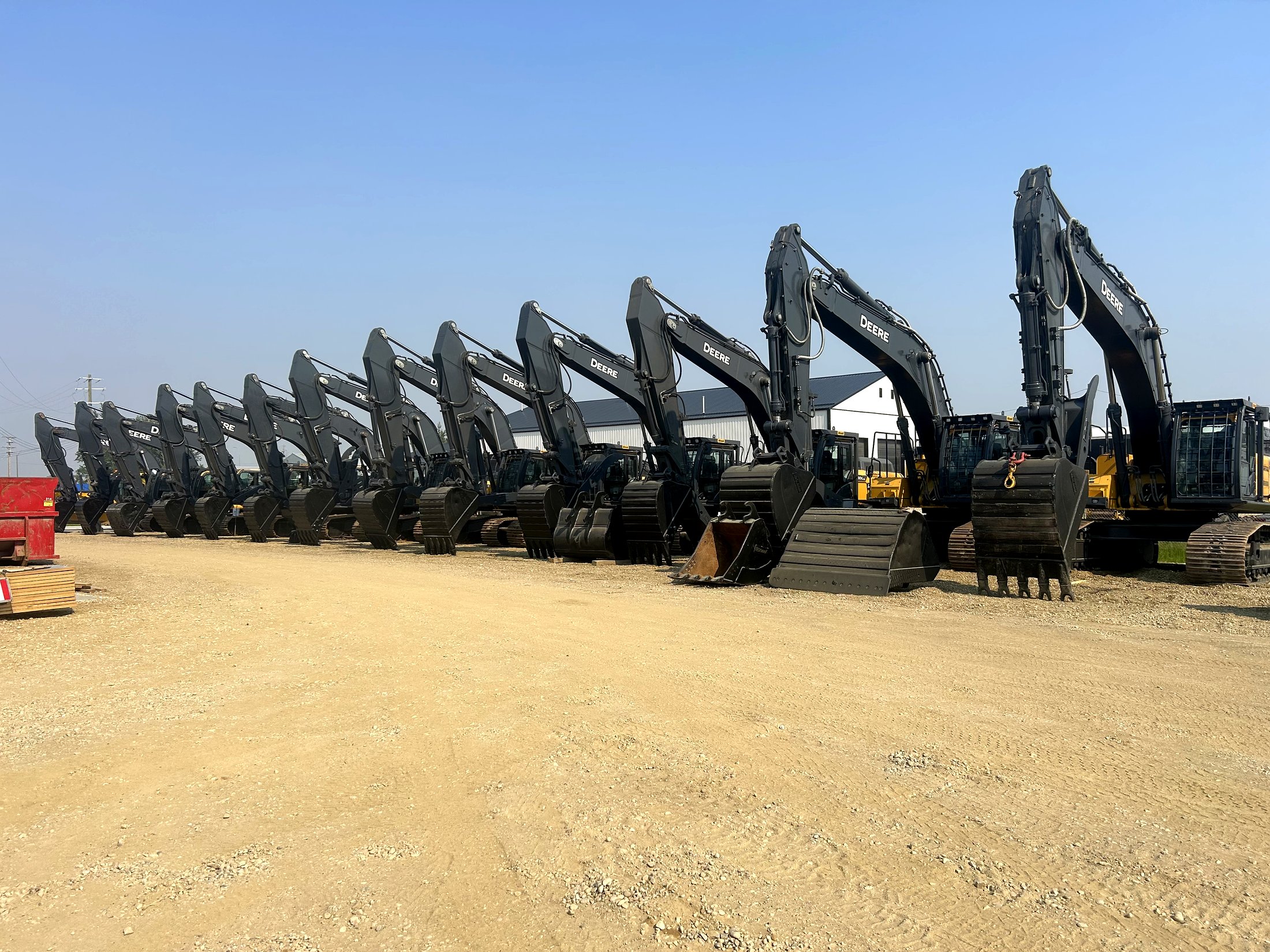 A row of John Deere excavators in the group fleet yard — real fleet equipment, not an SE installation